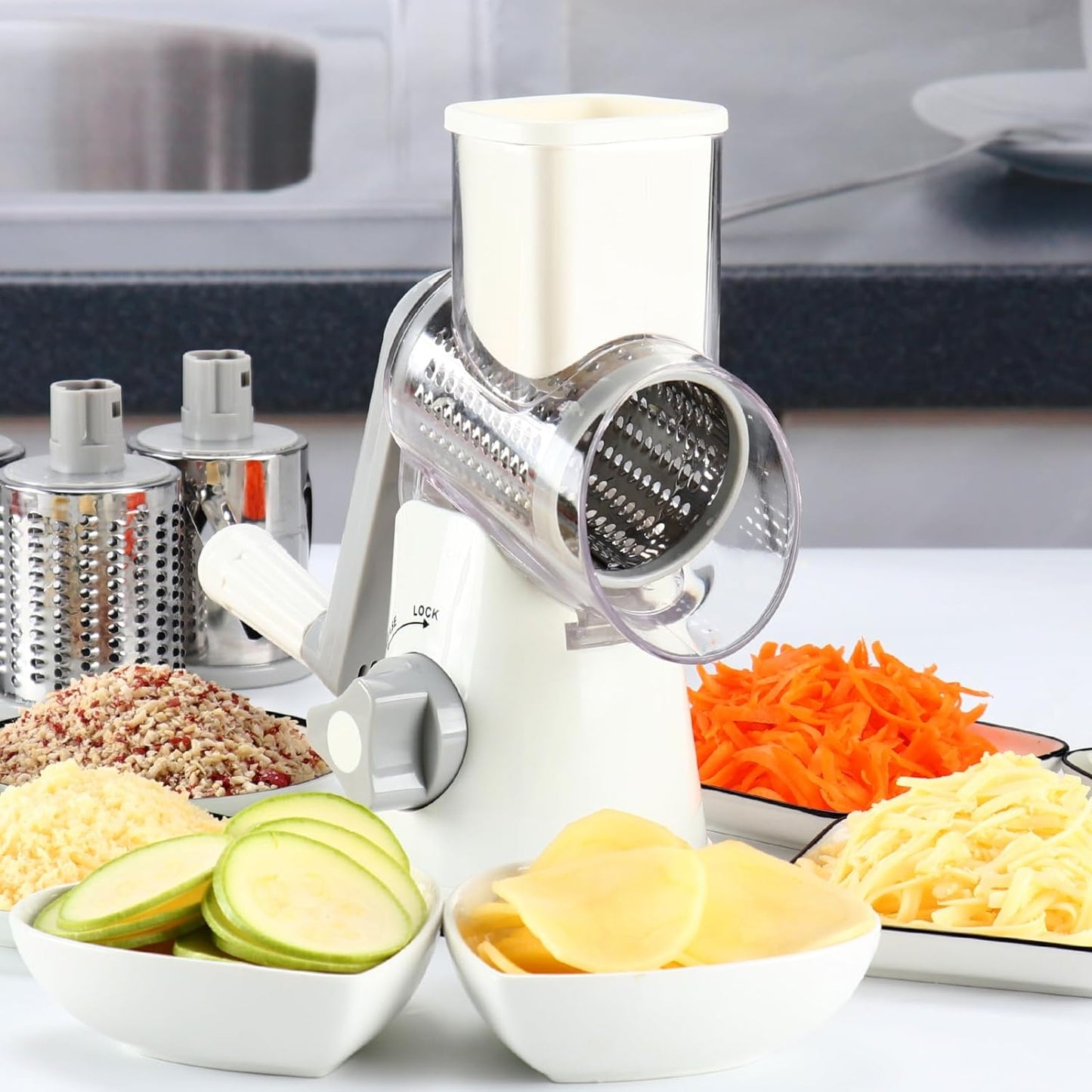 White rotary cheese grater with hand crank, three blades, non-slip suction base, for shredding cheese, vegetables, and nuts.