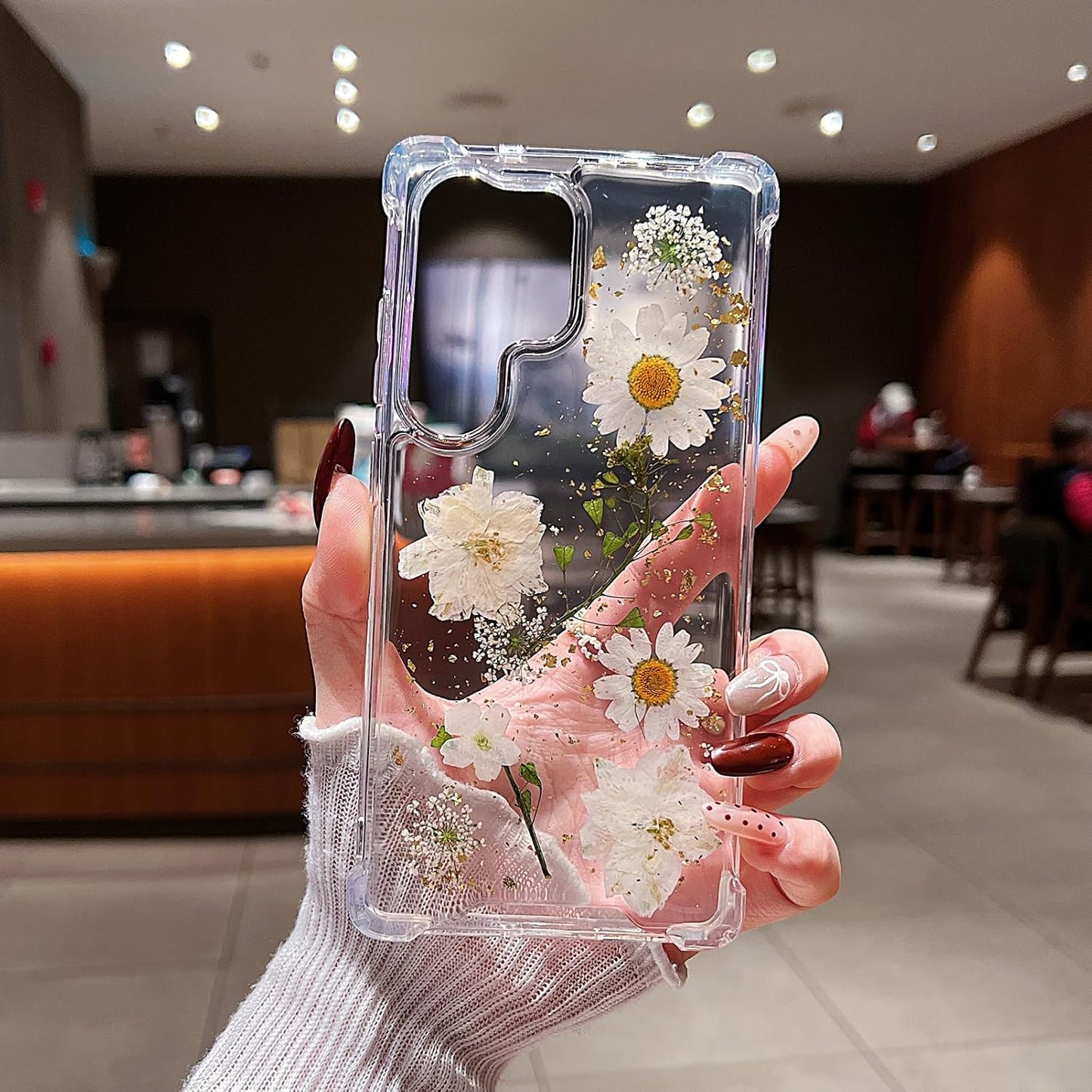 Clear Samsung Galaxy S26 Ultra case with pressed dried flowers design, featuring white floral accents and glitter for a feminine look.